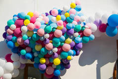 许多色彩艳丽的气球，在白墙背景上以心脏的形式出现.
