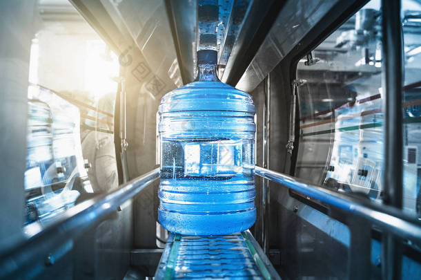 塑料瓶或一加仑的纯化饮用水在自动化输送机生产线内。水厂