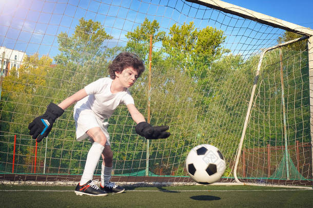 足球门的年轻守门员。 足球，足球运动员。 行动中的儿童