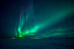 美丽的北极光在雪谷上空的风景照片