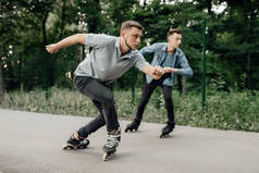 轮滑，两名男子滑雪者开始在夏季公园的速滑比赛。 城市轮滑、户外运动极限运动、轮滑