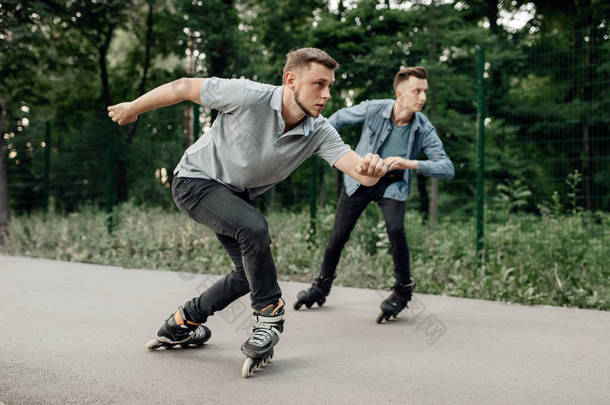 轮滑，两名男子滑雪者开始在夏季公园的速滑比赛。 城市轮滑、户外运动极限运动、轮滑