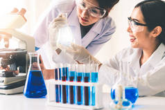一组身穿实验室外套的科学家在实验室工作，同时用试管和科学仪器检查生物化学样品。科学、技术和发展研究概念.