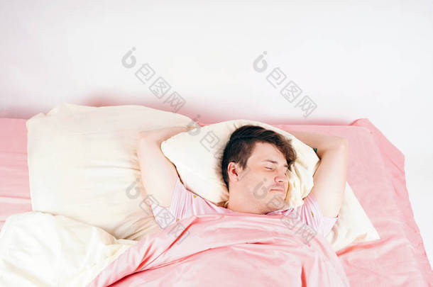 A young handsome man lies in bed and sweetly falls asleep. The man prepared for sleep, closing his e