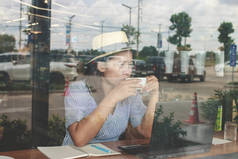 亚洲妇女戴着帽子在咖啡店的笔记本电脑上工作.