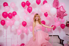 一个穿着粉色球衣，背靠气球的年轻女子。 漂亮的姑娘穿着晚上蓬松的云彩裙,戴着粉色和白色的气球. 女孩穿上华丽的球衣