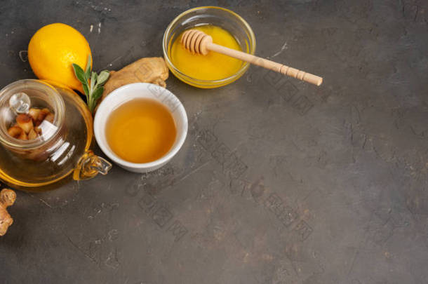 用新鲜生姜、柠檬草、鼠尾草、蜂蜜和柠檬，在深色背景下，用复制空间制作健康的抗氧化剂和抗炎姜茶.