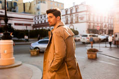 穿着风衣自信地穿过城市街道的年轻貌美男子的背影
