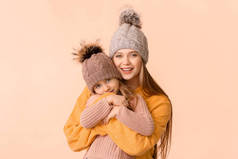 穿着彩色背景冬季服装的妇女和她的小女儿
