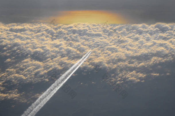 日落时云层上方有蒸气的客机的高角度视图
