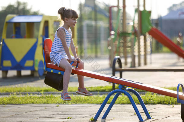 可爱的幼儿女孩户外在阳光明媚的夏天<strong>跷跷板</strong>摆动