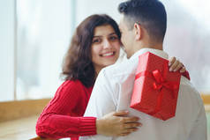 幸福的一对，抱着礼物。 红礼盒在一对相爱的夫妇手里。 情人节，节日和惊喜的概念。 情侣们互赠礼物。 关系和爱情概念.