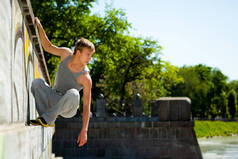 夏日晴空万里，身穿运动服的年轻人在外面的石墙上练习轮滑