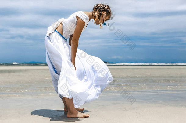 在海滩上摆姿势的年轻漂亮女子的风景画