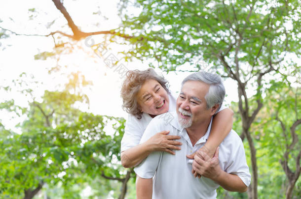 老年妇女骑着老年男子在公园里，带着爱和幸福。一对年长的亚洲夫妇身体很健康，笑脸。老夫妇总是呆在一起。外婆，外公都长命<strong>百岁</strong>了