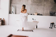 美丽的女人穿着白色浴衣在浴池边放松