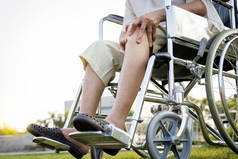 亚洲老年妇女坐在轮椅上，因为腿膝盖疼痛，双手托着膝盖，老年人膝关节剧烈疼痛，骨头问题，身体受伤，老年人患有关节炎，风湿病