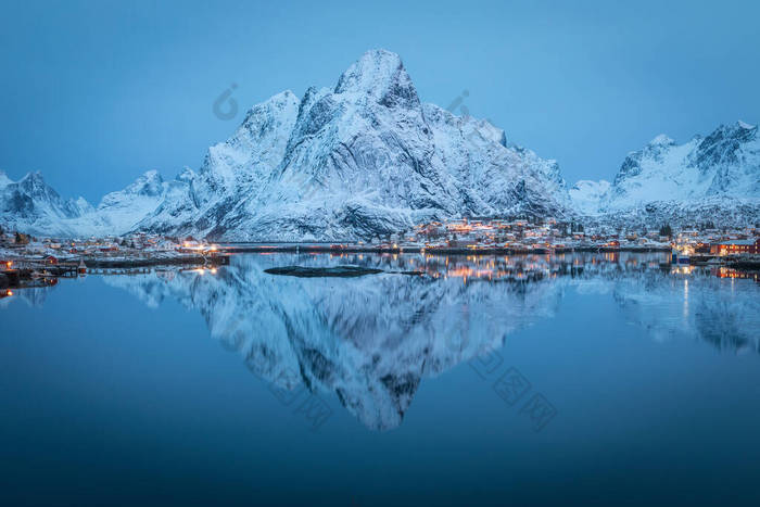 覆盖在高山上的大雪在遥远的北方峡湾平静而寒冷的海水中反射出来。黎明时分的渔村来自北极圈罗浮敦的宁静场景.