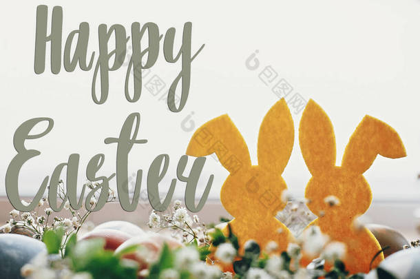 复活节快乐短信复活节贺卡。时尚的复活节彩蛋，黄色的兔子在春天花朵的窝在乡村的桌子上。天然染色的复活节彩蛋和兔子.假日卡片