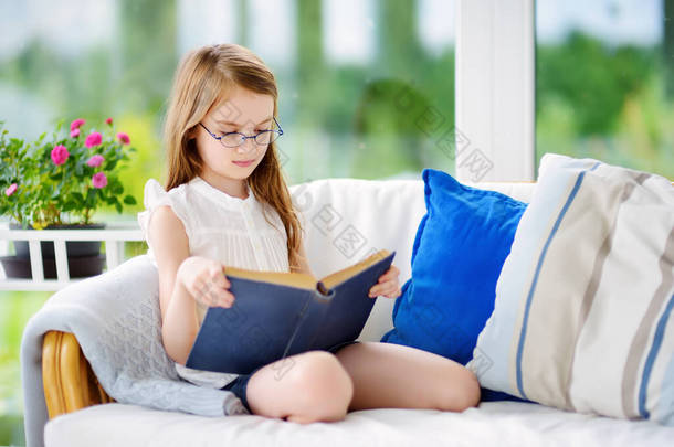 小女孩在客厅里看书。聪明的女学生放学后做作业.<strong>儿童</strong>的教育和远距离<strong>学习</strong>。检疫期间在家<strong>学习</strong>。待在家里娱乐.