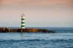 葡萄牙法罗市的海滩上矗立着一座条纹灯塔。漆黑的夜晚，大海中的小浪花