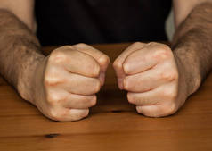 两只手握着木桌紧紧抓住毛茸茸的男人拳头象征愤怒的特写