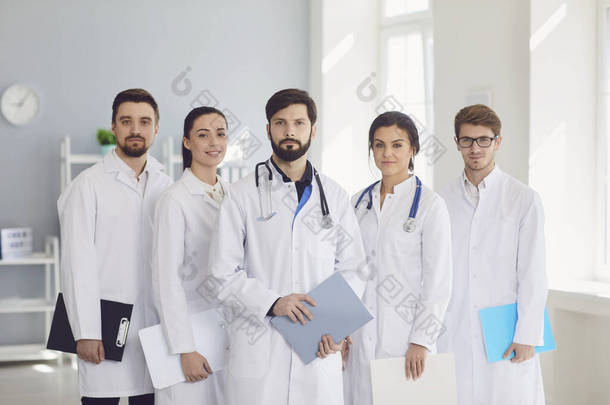 一群身穿白衣、自信的执业医生在诊所的背景下微笑着.
