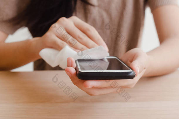 亚洲妇女在使用酒精喷雾在组织清洁<strong>手机</strong>之前，使用它保护验尸官。在与他人保持距离和自我检疫时间时，<strong>女性</strong>清洁的表面.
