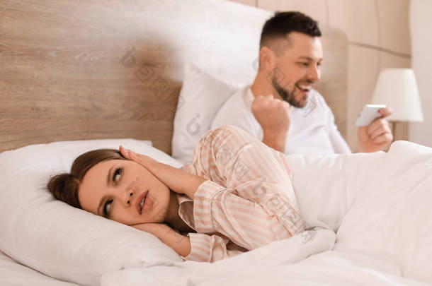 由于丈夫在卧室里用手机玩游戏，年轻女人睡不着觉