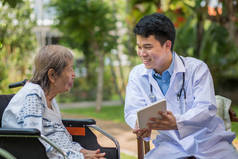 亚洲医生与坐轮椅的老年女性病人交谈