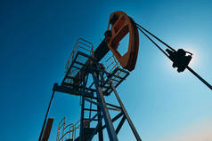 油泵在蓝天的背景下工作.世界石油工业。哈萨克斯坦西部地区：油泵是油井内往复式活塞泵的地面驱动装置.