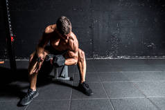 年轻强壮的肌肉汗液适合男子二头肌交叉训练与沉重的哑铃在健身房黑暗的形象与影子真实的人