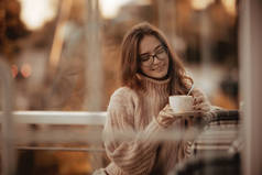 快乐女孩秋天咖啡店的概念视觉模型与眼镜摆姿势