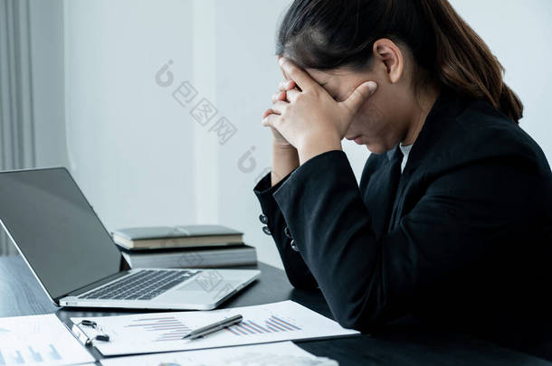 一位因工作而头疼的疲倦的女商人坐在写字台前.