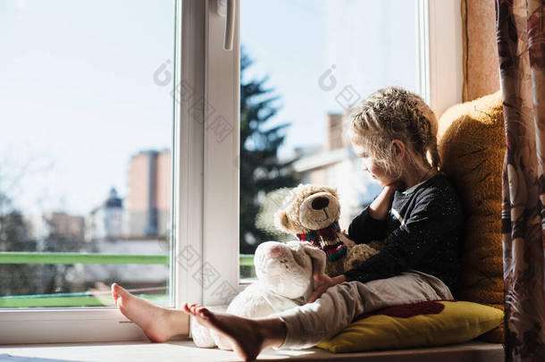 可爱的小女孩坐在<strong>窗边</strong>享受阳光。那孩子坐在一个大<strong>窗</strong>台上玩耍。维生素D
