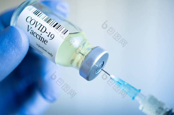 医生从玻璃瓶中提取Covid-19疫苗，并为疫苗注射填充注射器。在实验室里戴着防护的<strong>一次性手套</strong>，手部紧闭，并拿着一瓶疫苗药物。带着蓝色手术<strong>手套</strong>的手