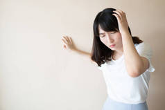 年轻的亚裔女性患有头晕、眩晕和头痛，背景呈白色。头晕的原因包括偏头痛、压力、中风、脑膜炎或脑瘤。保健问题.