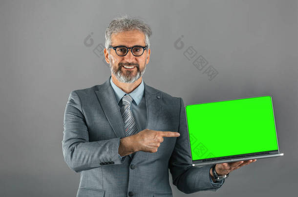 商务人员手持带有绿色屏幕的笔记本电脑的摄影棚照片