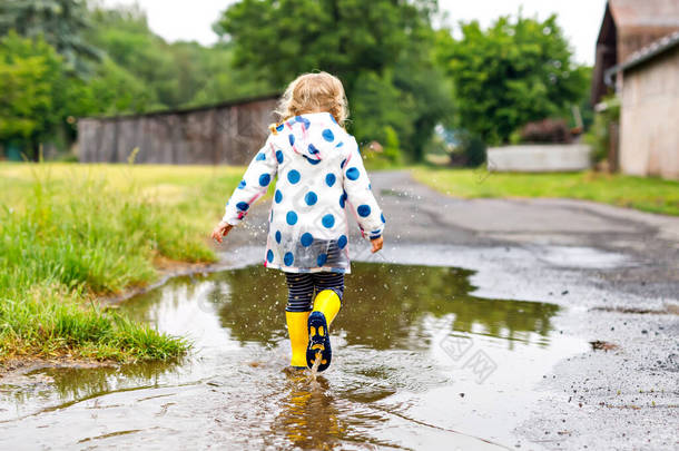 <strong>小孩子</strong>穿着黄色雨靴，在多雨天的雨夹雪中跑来跑去。可爱快乐的孩子穿着五颜六色的衣服跳进水坑里，泼洒着水，参加户外活动
