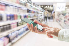 数码生活方式商业人士或购物人士在超级市场使用流动电话购物