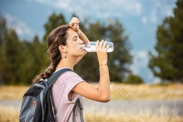 疲惫不堪的女旅行者在路上喝水喝水