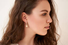 一个戴着珠宝的年轻漂亮姑娘的时髦画像.带有白色水晶和钻石的耳环.