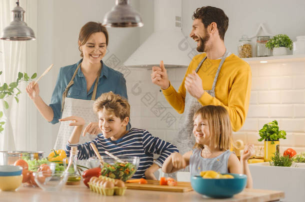 在《厨房：四个家庭一起做饭健康的晚餐，游手好闲，跳舞》中。妈妈，爸爸，小男孩和小女孩，准备沙拉，切蔬菜。可爱的孩子们帮助他们有爱心的父母