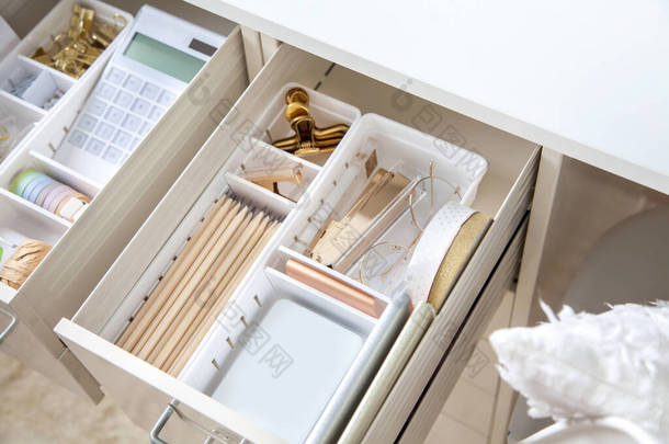女性工作场所。白色工作台时髦的金色文具整齐地摆放在桌子的抽屉里。日本储存方法.