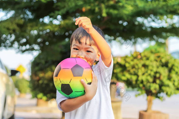 5个男孩的肖像形象。快乐的亚洲小孩手里拿着足球玩具玩耍。他穿着白衬衫在操场上玩耍.快乐和微笑的男孩。体育与儿童概念.