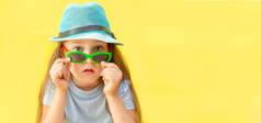 旅行的概念。一个戴着蓝色帽子、戴着黄色背景眼镜的女孩的画像.