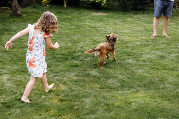 一个可爱的<strong>小女孩</strong>和她的<strong>宠物狗</strong>在家里的草地上玩耍.