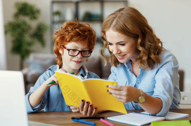 年轻妈妈帮小儿子在眼镜上做作业，一边看着儿子的笔记本，一边在<strong>网上学习</strong>