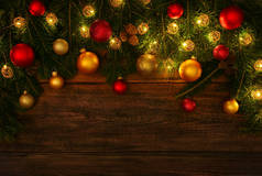 用圆锥、灯、彩球和灌木装饰的新鲜绿色云杉或松树圣诞树枝条，盖在带有复制空间的深褐色木板背景上