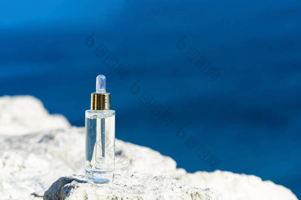 天然石上透明玻璃瓶中的化妆品血清。蓝海背景,自然护肤<strong>产品</strong>的概念.美丽健康肌肤的<strong>瘦身</strong>精华